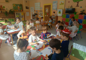 Dzieci siedzą przy stolikach i wykonują prace plastyczne inspirowane motywem kropki.