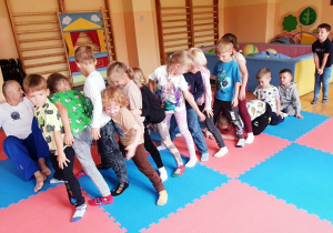 Przedszkolaki ćwiczą gibkość i koordynację ruchową, przechodząc pod nogami kolegów