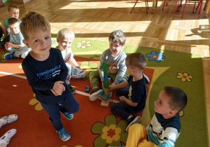 Przedszkolaki uczestniczą w konkurencji drużynowej, wspólnie budując wieżę z klocków.