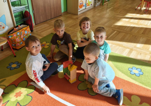 Przedszkolaki uczestniczą w konkurencji drużynowej, wspólnie budując wieżę z klocków.