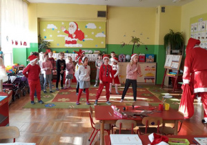 przedszkolaki z najstarszej grupy witają wchodzącego do sali Mikołaja piosenką