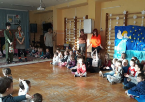 dzieci zgromadzone na przedszkolnej sali gimnastycznej spiewają kolędę z harcerzami