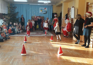 konkurencja "Mikołajkowa" - dzieci ustawione w dwóch rzędach biegną slalomem wokół pachołków