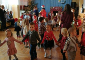 dzieci trzymają się za ręce, tańczą do świątecznej muzyki