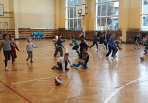 dzieci podczas zabawy z piłkami na sali gimnastycznej