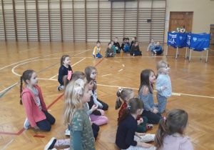 dzieci podzielone na dwa zespoły słuchają wskazówek trenera