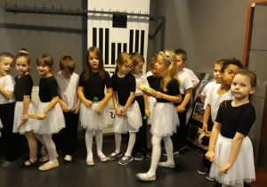 dzieci ubrane w czarno-białe stroje czekają na występ