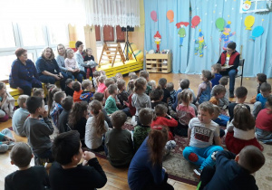 dzieci słuchają bajki czytanej przez starszego kolegę