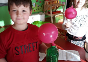 chłopiec demonstruje butelkę z balonem