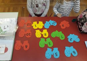 kolorowe rekawiczki - dziewczynki odczytują zapis graficzny cyfry znajdującej sie na rękawiczce i łączą w pary z odpowiednią liczbą śnieżynek