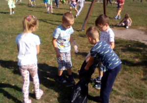 Dzieci zbierają śmieci na osiedlowym placu zabaw