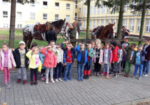 grupa dzieci pozuje na tle koni