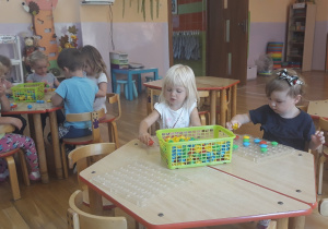 dzieci siedzą przy stoliku i układają klocki