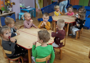 dzieci siedzą przy stolikach, jedzą lizaki