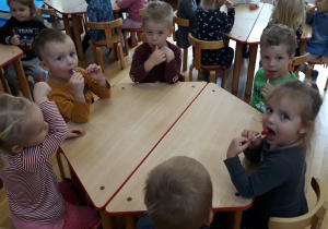 dzieci siedzą przy stolikach z lizakami