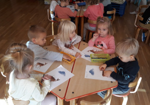 dzieci siedzą przy stolikach i malują