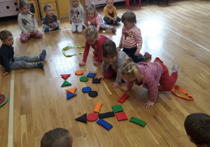 dzieci na podłodze układają obrazek z figur geometrycznych