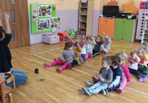 dzieci w dwóch rzedach siedzą na podłodze