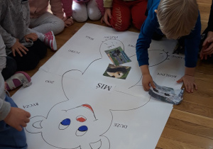 dzieci przyklejają na kartonie wiadomości o niedźwiedziach i misiach