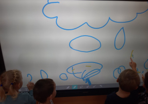 dzieci rysują na tablicy krople deszczu