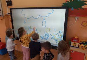 dzieci malują na tablicy krople deszczu