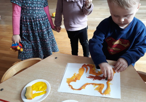 dzieci maluja gąbką umoczoną w farbie kontur psa