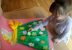 dziewczynka wykleja kwiatkami suknię Pani Wiosny