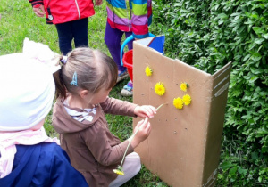 dziewczynka przyczepia kwiatka do kartonu