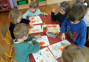dzieci ozdabiają wiewiórkę pomarańczową bibułą