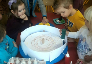 dzieci tworzą tęczowe barwy przy pomocy maszyny