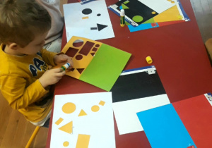 dzieci wykonują pracę plastyczną z kolorowych figur geometrycznych