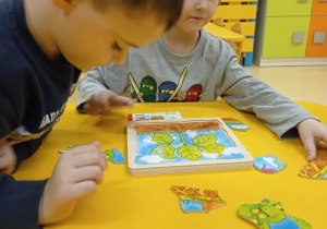 chłopcy układają puzzle