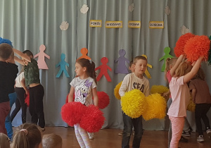 dzieci tańczą z kolorowymi pomponami
