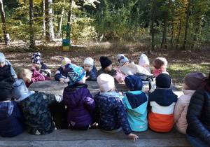 dzieci siedza przy drewnianych ławach