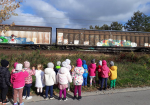 dzieci obserwują nadjeżdżający pociąg towarowy
