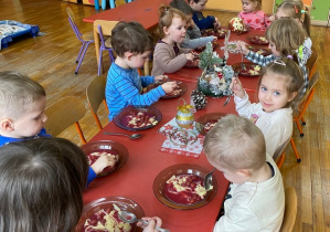 dzieci siedza przy stole i jedzą obiad