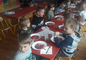 dzieci siedza przy stole i jedzą obiad