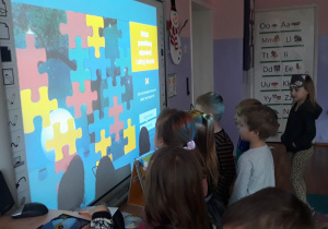 dzieci rozwiazuja zagadki na tablicy interaktywnej