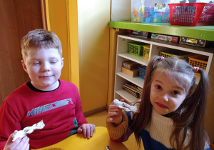 dzieci siedzą przy stoliku i jedzą racuszki