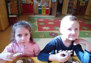 dzieci siedzą przy stoliku i jedzą racuszki