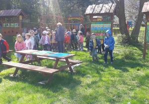 dzieci w ogrodzie przedszkolnym szukają skarbów Ziemi i zaznaczają na kartce