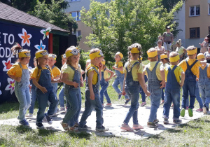 dzieci ubrane w niebieskie ogrodniczki i żółte bluzeczki podczas występów