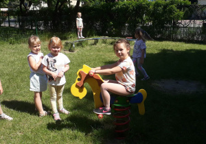 dzieci korzystają z urządzeń rekreacyjnych znajdujących się w naszym ogrodzie przedszkolnym, bawią się na koniku