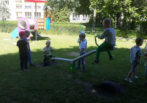 dzieci korzystają z urządzeń rekreacyjnych znajdujących się w ogrodzie przedszkolnym