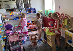 dziewczynki bawią się lalkami i wózkami w kąciku zabaw
