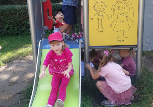 dziewczynka w różowym stroju bawi się na zjeżdżalni