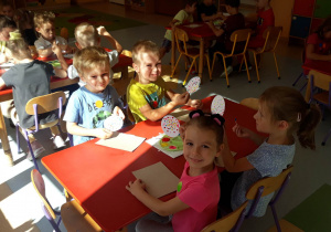 dzieci siedzą przy stolikach, wykonują pracę plastyczną farbą stęplują szablon koła