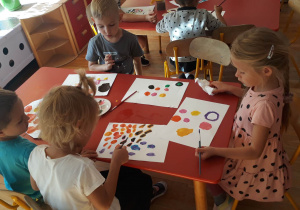 dzieci malują farbami kolorowe kropki, tworza prace plastyczne