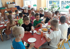 przedszkolaki siedzą przy stole na którym leży słodki poczęstunek