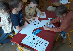 dzieci siedza przy stolikach, rysują trasę dla ozobota